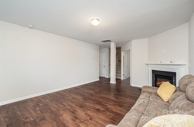 living room with dark wood-type flooring, baseboards, and a glass covered fireplace