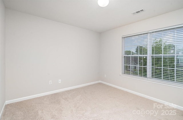 carpeted empty room featuring baseboards