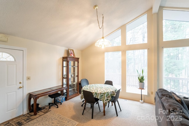 dining space featuring plenty of natural light, carpet floors, a chandelier, and high vaulted ceiling