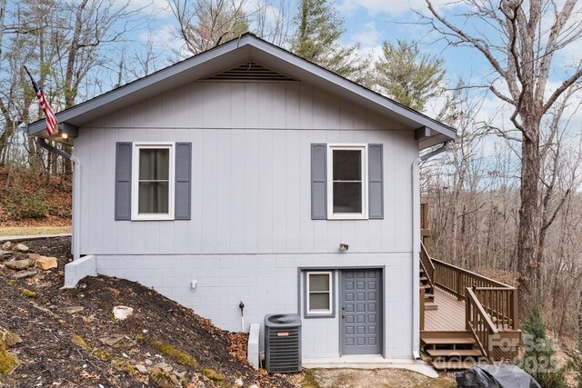 view of property exterior with central air condition unit, a deck, and stairs