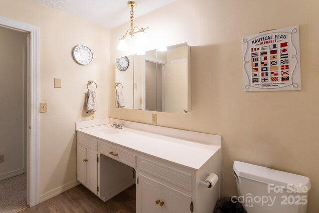 bathroom featuring wood finished floors, vanity, toilet, and baseboards