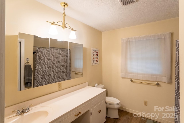 full bathroom with wood finished floors, toilet, vanity, a textured ceiling, and baseboards