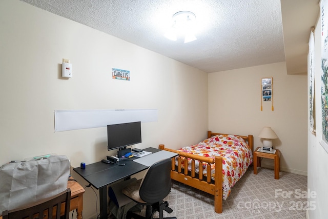 carpeted bedroom with a textured ceiling and an office area