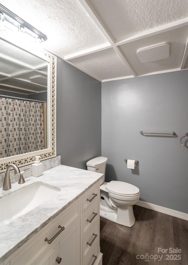 bathroom with wood finished floors, toilet, vanity, curtained shower, and baseboards