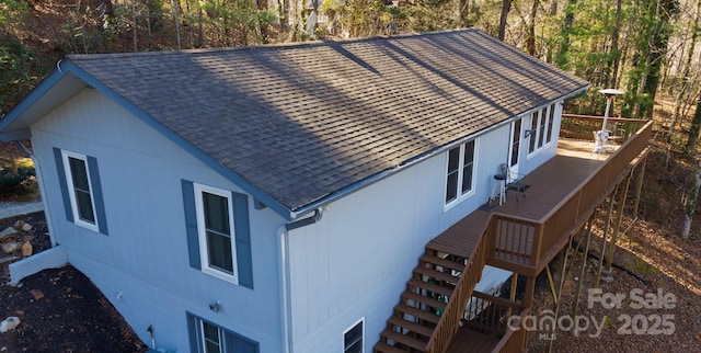view of side of property with roof with shingles, stairs, and a wooden deck