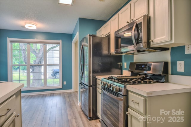 330 Kilmer Ln, Mooresville, NC 28115 - kitchen with appliances with stainless steel finishes, light countertops, light wood finished floors, a textured ceiling, and white cabinets