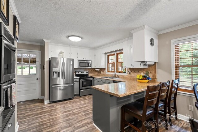 603 Sunnybrook Dr, Monroe, NC 28110 - kitchen with stainless steel appliances, a sink, a peninsula, ornamental molding, and decorative backsplash