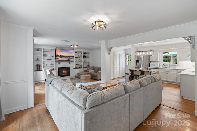 1014 Vandalia Dr, Charlotte, NC 28212 - living area featuring a glass covered fireplace, light wood finished floors, ornamental molding, and built in features