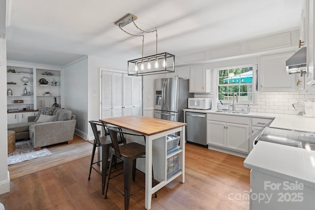 1014 Vandalia Dr, Charlotte, NC 28212 - kitchen with stainless steel appliances, a sink, exhaust hood, and light wood-style floors