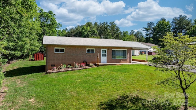 rear view of property featuring brick siding, a storage unit, a yard, and an outbuilding