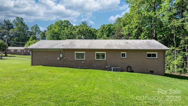 rear view of house with a lawn, crawl space, cooling unit, and brick siding