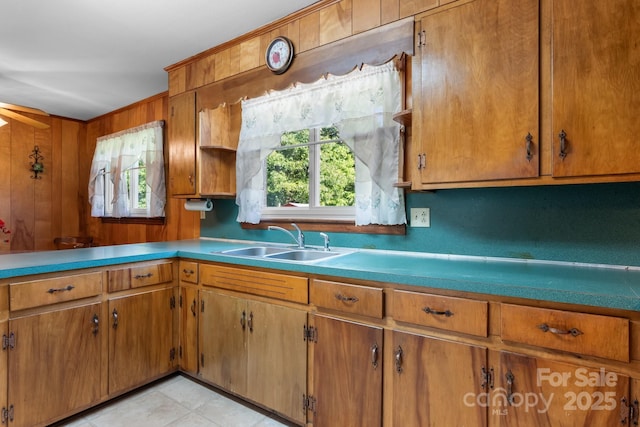 kitchen featuring a sink, brown cabinetry, and wooden walls