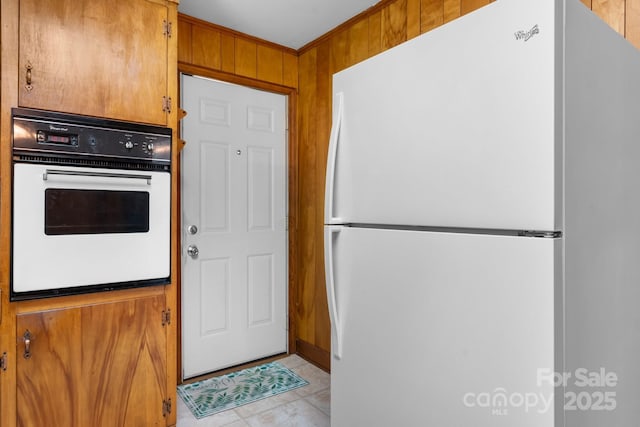 kitchen with white appliances, brown cabinets, ornamental molding, and wood walls