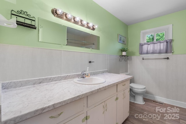 bathroom featuring a wainscoted wall, vanity, toilet, and wood finished floors