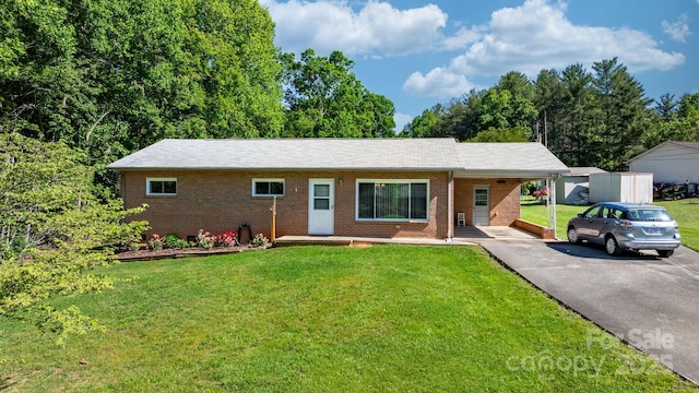 ranch-style home featuring brick siding, driveway, a front lawn, and a carport