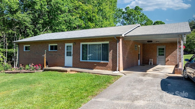 single story home with driveway, a front lawn, a carport, and brick siding
