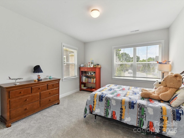 carpeted bedroom featuring multiple windows and baseboards