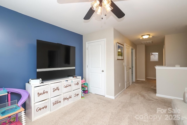 recreation room with light colored carpet, ceiling fan, and baseboards