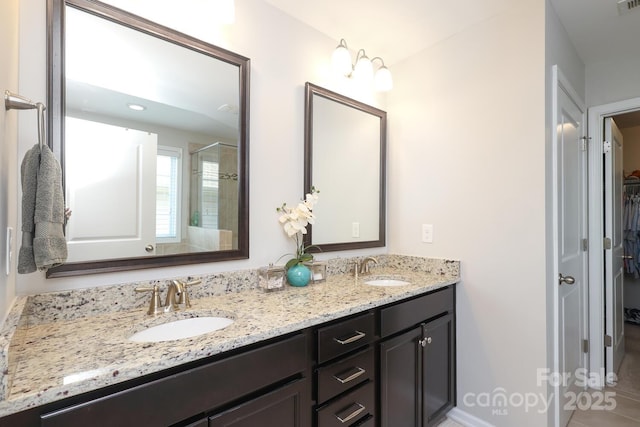 bathroom with double vanity, an enclosed shower, and a walk in closet