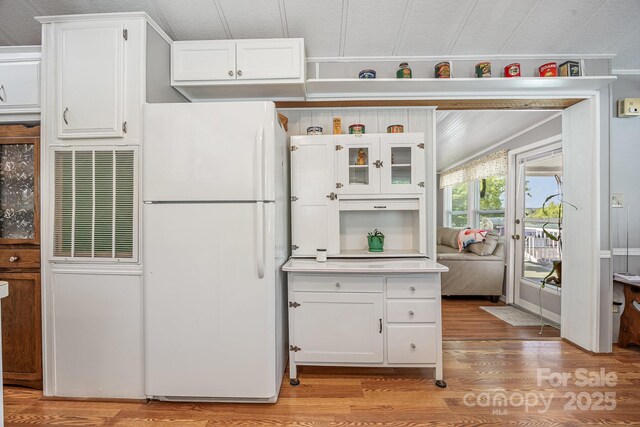125 Maple St, New London, NC 28127 - kitchen with freestanding refrigerator, light wood-type flooring, white cabinets, light countertops, and crown molding