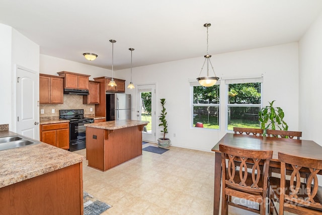 12792 Clydesdale Dr, Midland, NC 28107 - kitchen with black range with electric cooktop, freestanding refrigerator, brown cabinets, under cabinet range hood, and a kitchen island