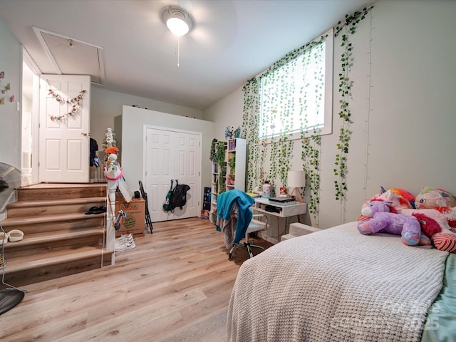 bedroom featuring light wood-style flooring, a closet, attic access, and ceiling fan