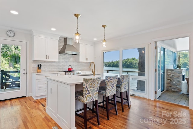 6664 Lake Shore Dr, Hickory, NC 28601 - kitchen featuring wall chimney range hood, a sink, light countertops, a center island with sink, and backsplash