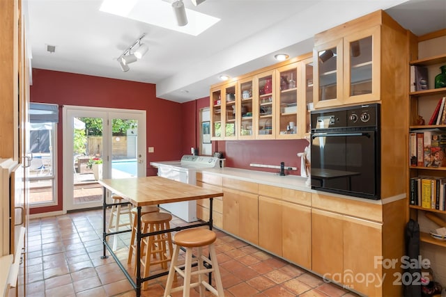 6664 Lake Shore Dr, Hickory, NC 28601 - kitchen with black oven, independent washer and dryer, a skylight, light tile patterned floors, and light countertops