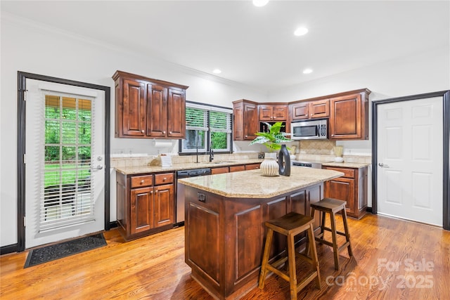 4339 Shannamara Dr, Matthews, NC 28104 - kitchen featuring stainless steel appliances, a sink, backsplash, light wood-style floors, and ornamental molding