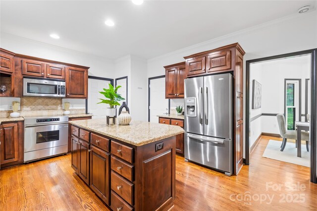 4339 Shannamara Dr, Matthews, NC 28104 - kitchen featuring stainless steel appliances, decorative backsplash, light wood finished floors, ornamental molding, and light stone counters