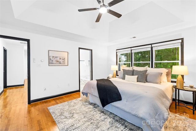 4339 Shannamara Dr, Matthews, NC 28104 - bedroom with a tray ceiling, light wood finished floors, connected bathroom, baseboards, and a ceiling fan