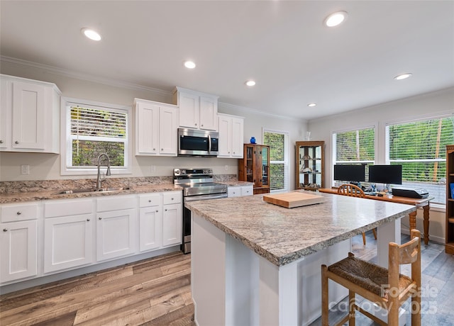 328 Mountain Lion Trl, Maggie Valley, NC 28751 - kitchen with appliances with stainless steel finishes, a sink, light wood-style flooring, ornamental molding, and a kitchen breakfast bar