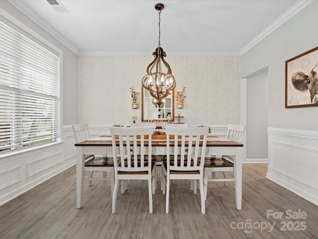 5013 Hamilton Mill Dr, Waxhaw, NC 28173 - dining area featuring a chandelier, a decorative wall, crown molding, wood finished floors, and wainscoting