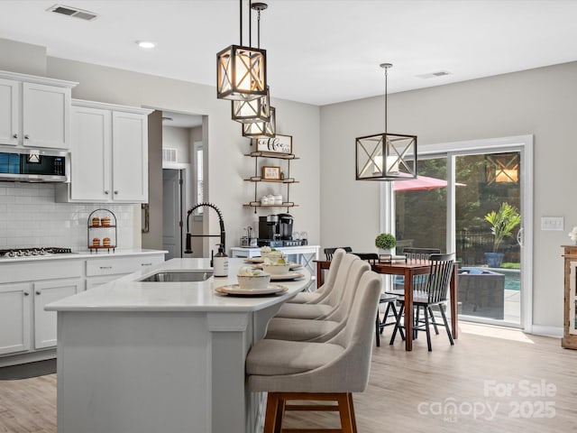 5013 Hamilton Mill Dr, Waxhaw, NC 28173 - kitchen featuring appliances with stainless steel finishes, light countertops, tasteful backsplash, light wood-style flooring, and an island with sink