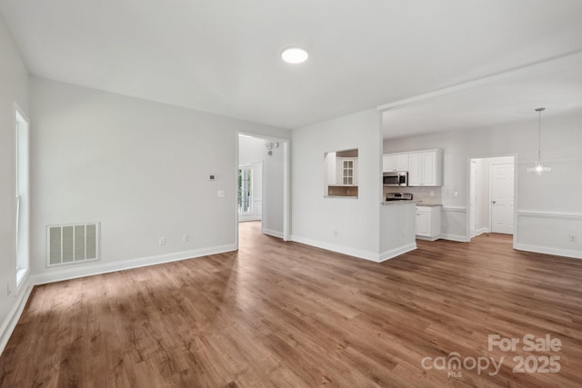 unfurnished living room featuring wood finished floors and baseboards