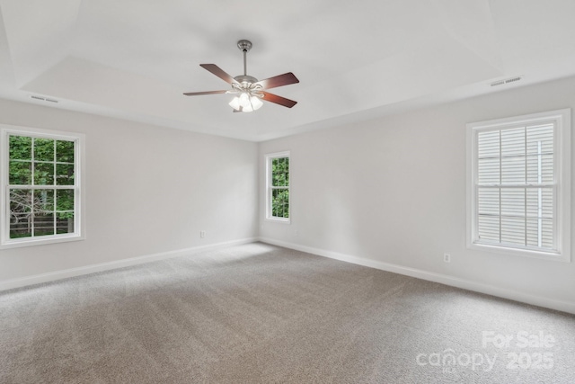 carpeted spare room featuring baseboards, a ceiling fan, and a tray ceiling
