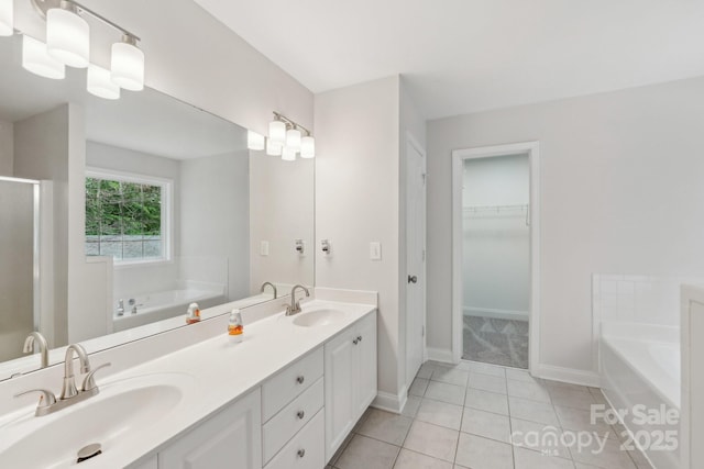 bathroom featuring a garden tub, tile patterned floors, baseboards, and a walk in closet