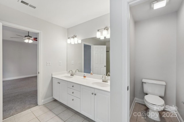 bathroom featuring tile patterned floors, toilet, double vanity, baseboards, and ceiling fan