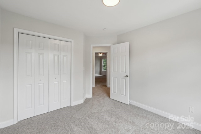 unfurnished bedroom with carpet, baseboards, and a closet