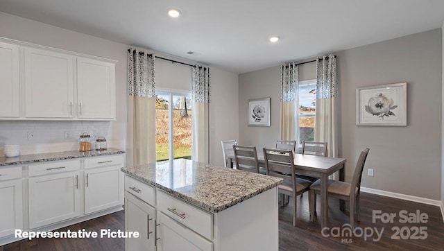 kitchen with dark wood-type flooring, tasteful backsplash, light stone countertops, a kitchen island, and recessed lighting