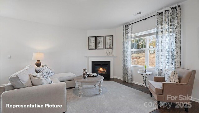 living area with wood finished floors, a fireplace with flush hearth, and baseboards
