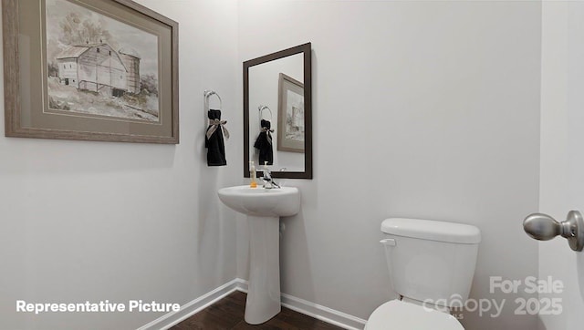 bathroom featuring wood finished floors, baseboards, and toilet