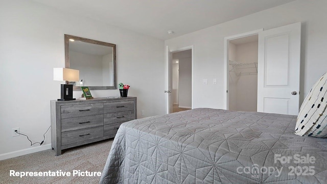 bedroom featuring light colored carpet, baseboards, and a spacious closet