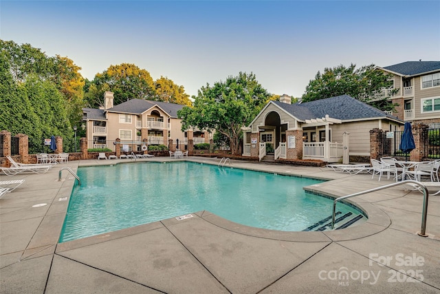 community pool with fence and a patio area