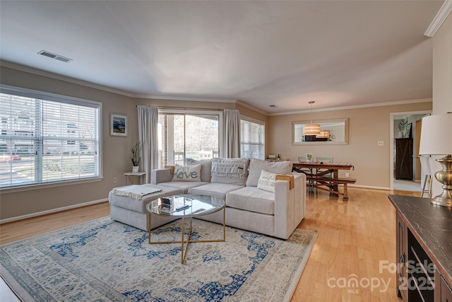 living area featuring light wood-type flooring, ornamental molding, and baseboards