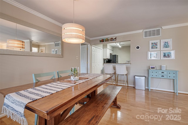 dining space featuring crown molding, light wood-type flooring, and baseboards