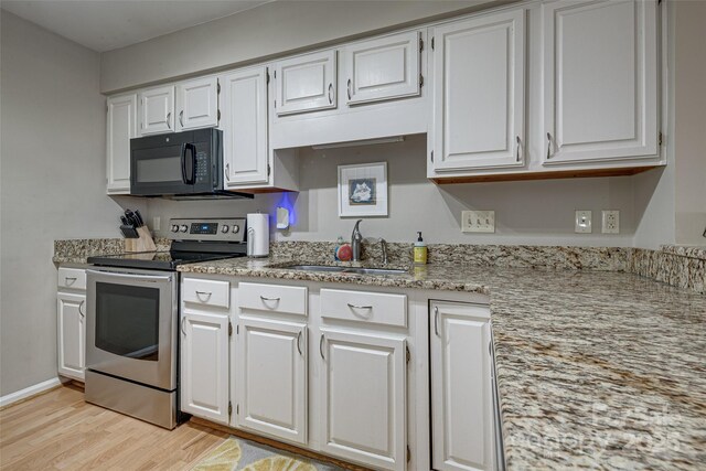 kitchen featuring black microwave, stainless steel electric range oven, a sink, and white cabinetry