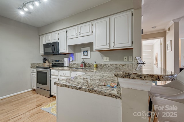 kitchen with stainless steel electric stove, black microwave, light wood-style flooring, light stone countertops, and white cabinetry
