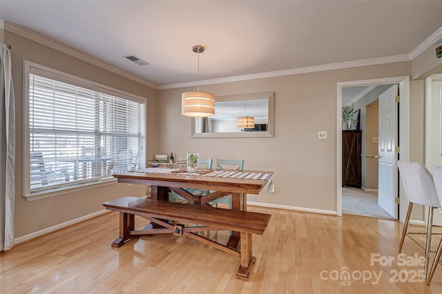 dining area with light wood-type flooring, baseboards, and crown molding
