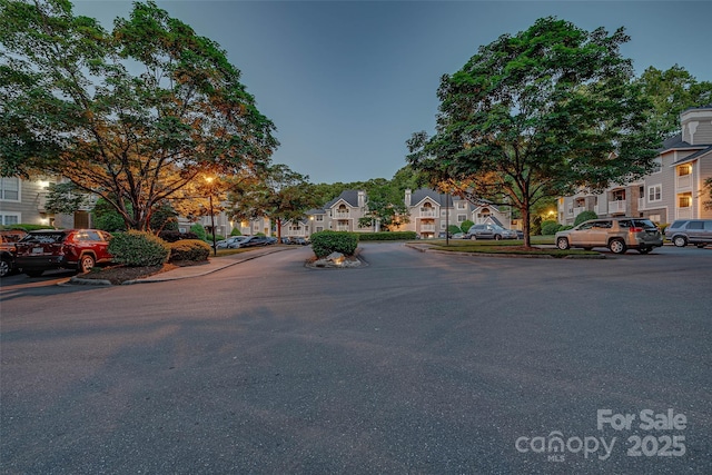 view of asphalt street with a residential view and curbs
